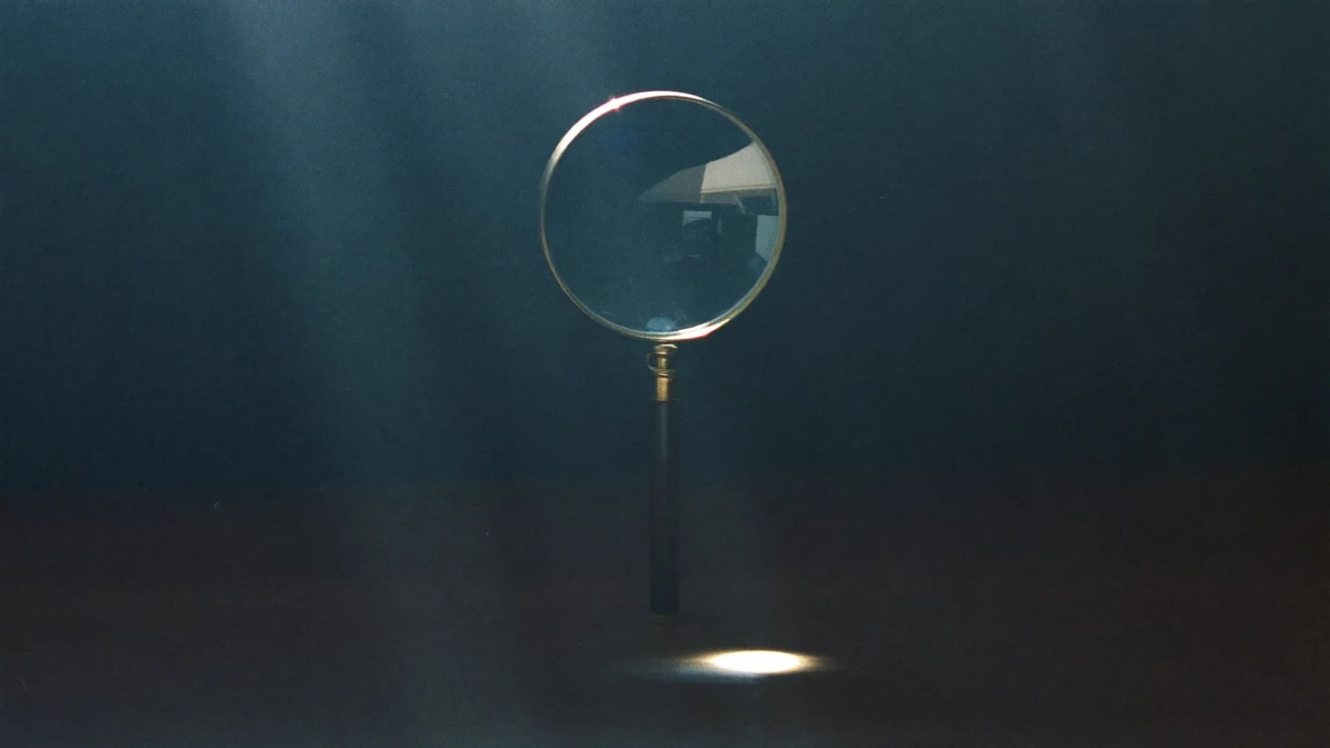 A brass loupe standing in a beam of light in a dark room